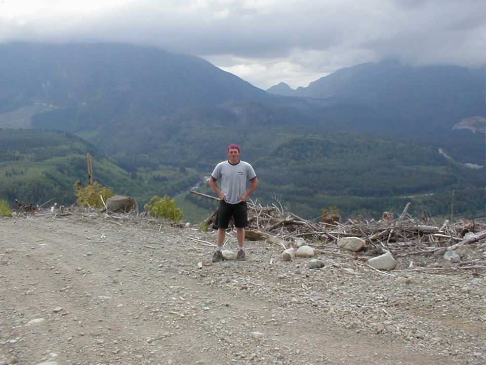 Person standing on a dirt road with mountains in the background