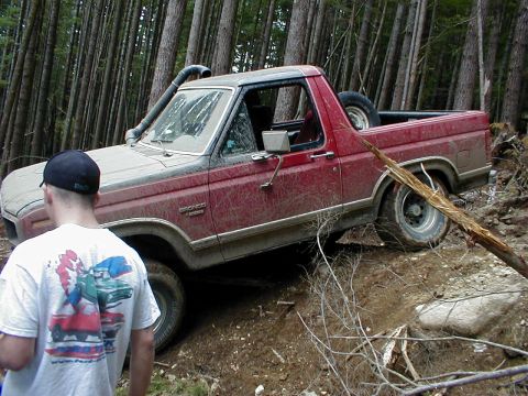 1983 Ford Bronco - A red Ford Bronco navigates a steep, wooded trail, its snorkel extended.