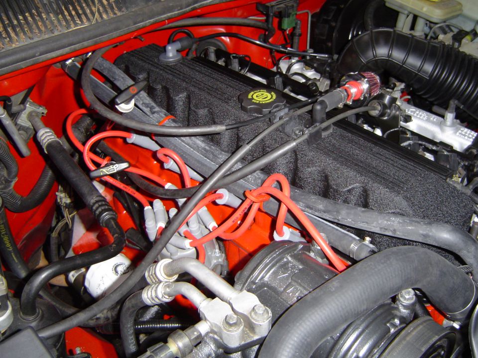 Engine bay with black plastic intake plenum, red ignition wires and red-painted firewall