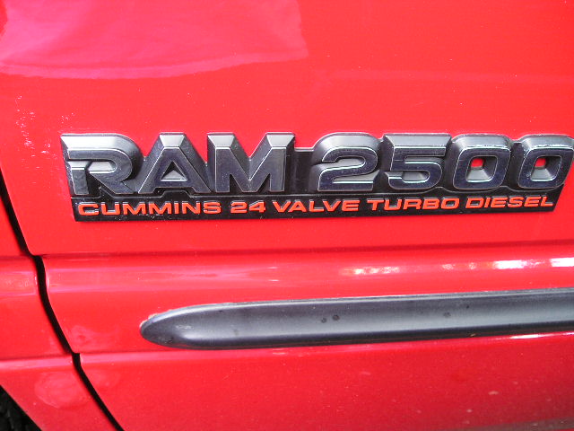 Close-up of a red truck's side showing a RAM 2500 Cummins 24 Valve Turbo Diesel badge