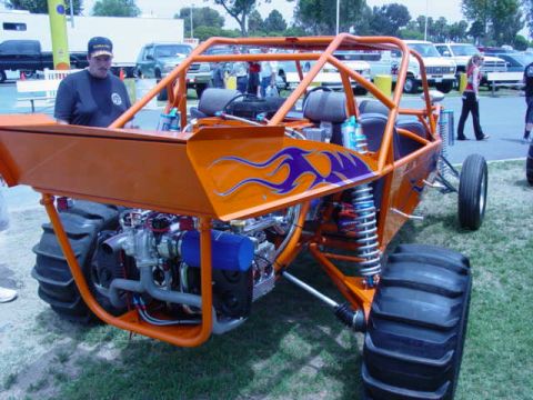 1992 Ford Bronco - An orange custom buggy with flame decals and a powerful engine is displayed at an outdoor event.