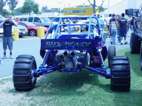 1992 Ford Bronco - A custom blue off-road buggy is viewed from the rear, large paddle tires and the phrase 'Blew Money' on its tailgate.