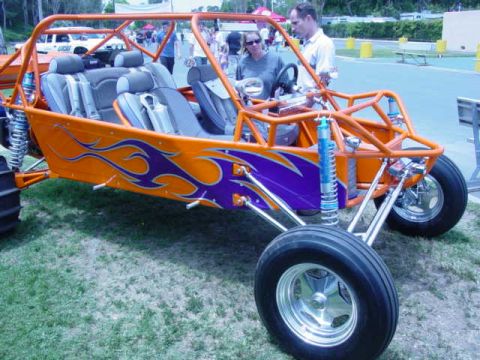1992 Ford Bronco - An orange off-road buggy with custom flame decals is displayed at an outdoor event.