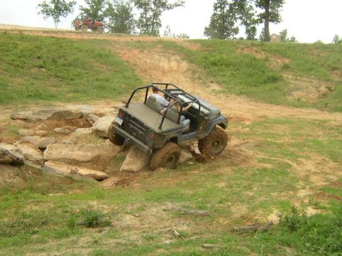 1995 Ford Bronco - A Jeep Wrangler tackles an off-road obstacle course with another vehicle visible in the background.