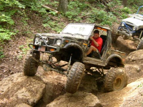1995 Ford Bronco - A driver navigates a off-road course in a modified Suzuki Samurai, with another vehicle following closely.