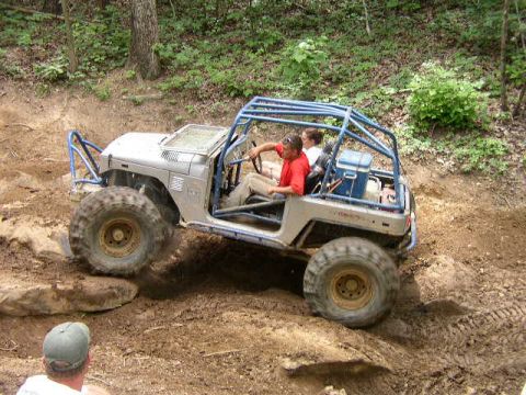 1995 Ford Bronco - Modified Jeep Wrangler navigating a rocky off-road trail with two occupants.