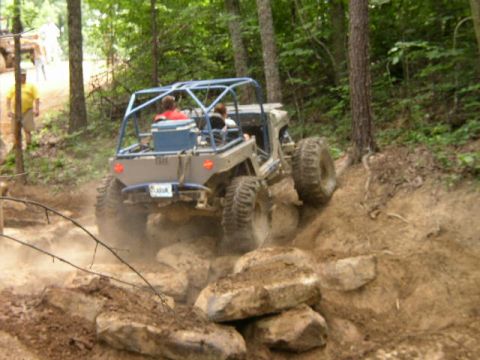 1995 Ford Bronco - This off-road buggy navigates a challenging rocky incline in a wooded area.