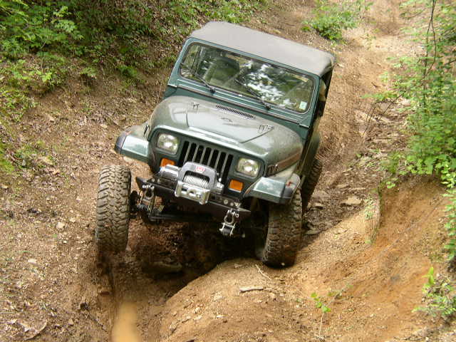 Green Jeep Wrangler with winch on a steep dirt trail