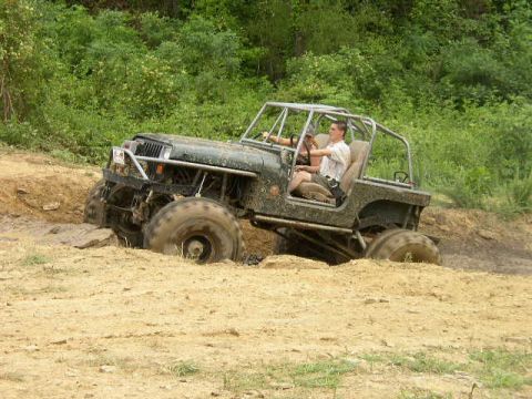 1995 Ford Bronco - A modified Jeep Wrangler tackles an off-road trail with a driver behind the wheel.
