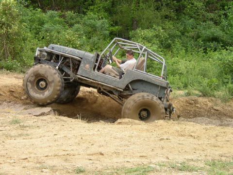 1995 Ford Bronco - A modified off-road vehicle with oversized tires maneuvers through a challenging dirt terrain.