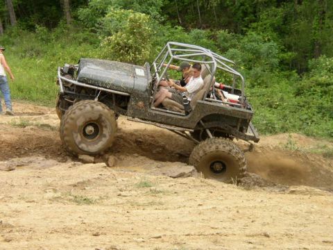 1995 Ford Bronco - Modified Jeep with roll cage navigates a dirt trail during an off-road excursion.