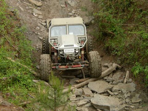 1995 Ford Bronco - This heavily modified off-road vehicle tackles a challenging rocky path, demonstrating its extreme suspension and tire capabilities.