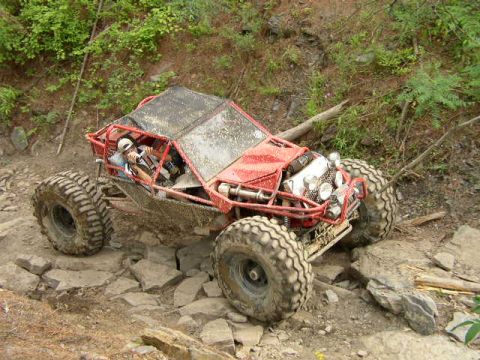 1995 Ford Bronco - Custom off-road buggy tackling a challenging rocky path in a wooded area.