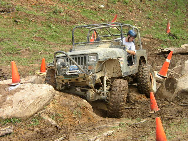 Off-road Jeep Wrangler navigating rocky terrain with orange cones