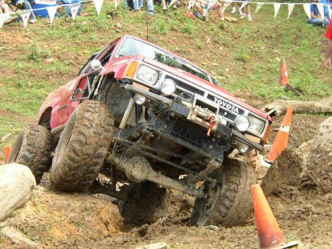 1995 Ford Bronco - This modified Toyota pickup truck is tackling a challenging off-road course with large tires and a lifted suspension.