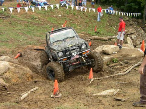 1995 Ford Bronco - An off-road vehicle attempts to traverse a challenging muddy and rocky terrain during an event.
