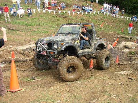 1995 Ford Bronco - A driver maneuvers a modified off-road vehicle through a challenging, muddy obstacle course.