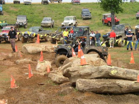 1995 Ford Bronco - Multiple off-road vehicles are seen navigating a challenging rocky terrain with orange cones marking the course.