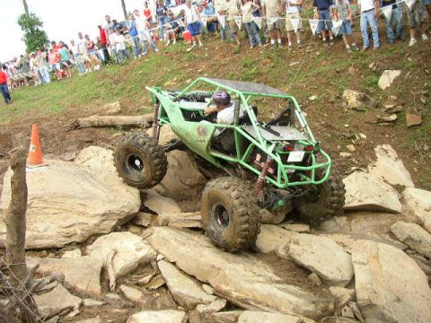 1995 Ford Bronco - A custom-built off-road buggy navigates a challenging rocky terrain with spectators watching from a hillside.