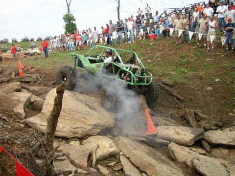 1995 Ford Bronco - An off-road buggy tackles a challenging rocky obstacle course with a crowd watching.