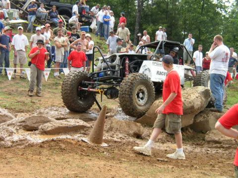 1995 Ford Bronco - A custom off-road buggy tackles a challenging obstacle course with a crowd gathered to observe the event.