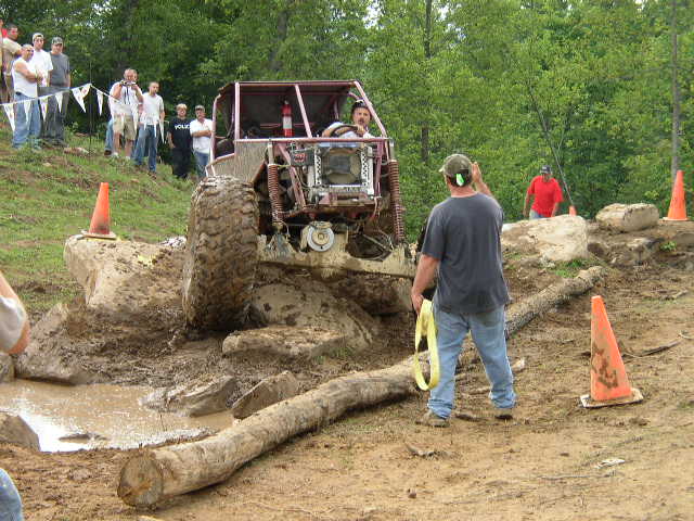 Off-road buggy stuck in mud with a person holding a tow strap