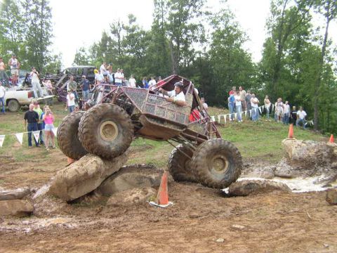1995 Ford Bronco - A custom off-road buggy navigates a challenging rock obstacle with spectators observing the event.