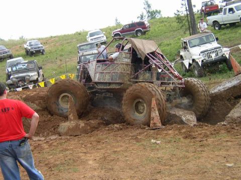 1995 Ford Bronco - Multiple off-road vehicles navigate a muddy course with large tires and custom modifications.
