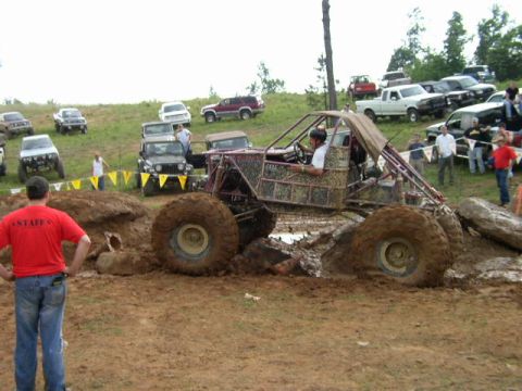 1995 Ford Bronco - A custom-built off-road buggy navigates a muddy obstacle course with onlookers observing the event.