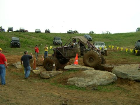 1995 Ford Bronco - Custom off-road buggy tackles a challenging rock obstacle during an event.