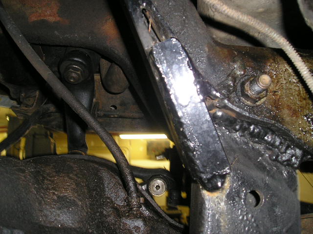 Close-up of greasy, black undercarriage components with visible welds and bolts