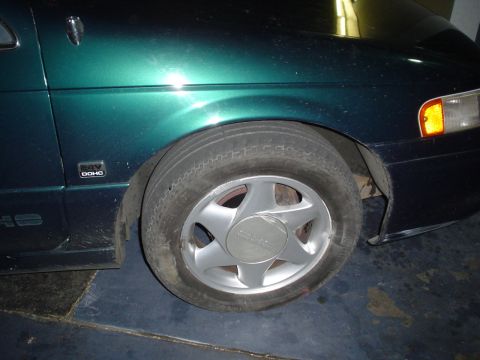 1993 Ford Taurus - A green 1993 Ford Taurus is shown from the front, focusing on the front wheel and fender area.