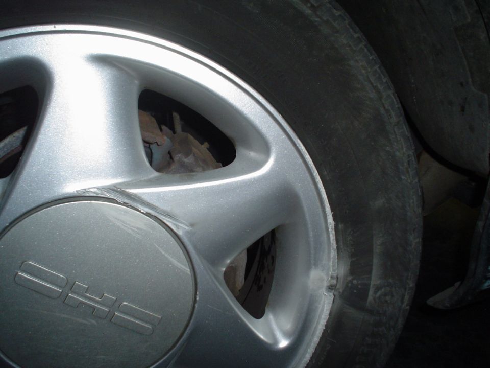 Close-up of a silver alloy wheel with 'DHS' text on the center cap, next to a worn tire