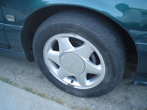 1993 Ford Taurus - A flat tire on a green 1993 Ford Taurus is visible on the side of the vehicle.