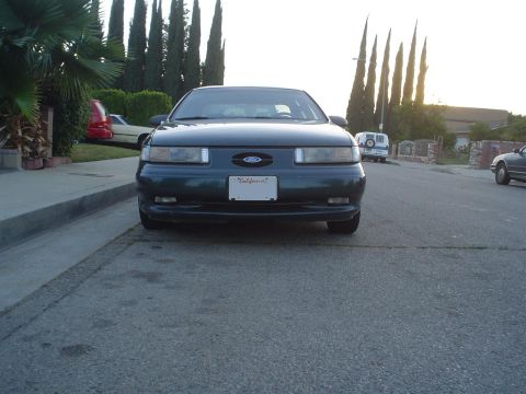 1993 Ford Taurus - Front view of a dark green Ford Taurus parked on a residential street.