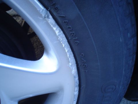 1993 Ford Taurus - Close-up of a damaged alloy wheel and tire, revealing tire size information.
