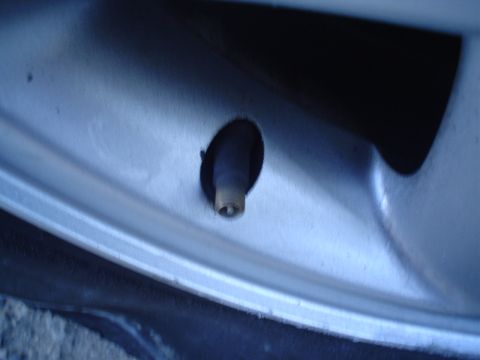 1993 Ford Taurus - Close-up of a tire valve stem on a silver alloy wheel.