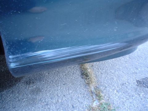 1993 Ford Taurus - The rear bumper of a 1993 Ford Taurus shows extensive damage from scuffs and scratches.