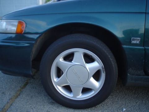 1993 Ford Taurus - Close-up of a green GMC Jimmy's front wheel and fender, showing the headlight and a "24V DOHC" badge.