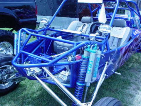 1992 Ford Bronco - A custom blue buggy with racing shocks is parked next to a dark-colored truck.
