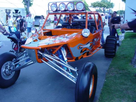1992 Ford Bronco - A custom orange dune buggy with flame graphics and large off-road tires is displayed at an outdoor event.