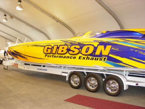 1992 Ford Bronco - A striking yellow and blue performance boat, branded "GIBSON Performance Exhaust," is displayed on a trailer.
