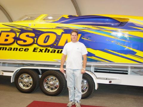 1992 Ford Bronco - Man stands beside a large boat on a trailer, bright yellow and blue graphics and text.