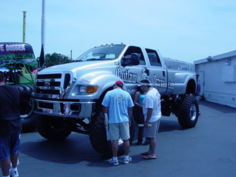 1992 Ford Bronco - A heavily modified Ford truck with large tires is displayed next to a monster truck.