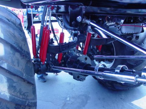 1992 Ford Bronco - Close-up of a monster truck's heavy-duty suspension system and massive tire.
