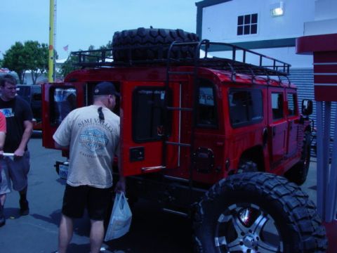 1992 Ford Bronco - A red Humvee is parked outside a building with people around it.