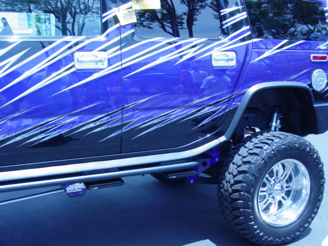 Blue SUV with custom silver and black graphics, lifted suspension, and large off-road tires