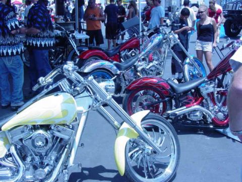 1992 Ford Bronco - A custom motorcycle with yellow and flame paint is displayed at an outdoor event with other vehicles and people.