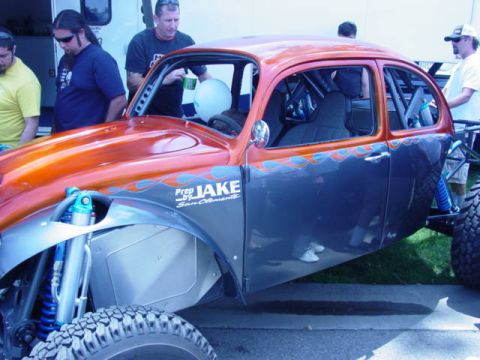 1992 Ford Bronco - Custom Volkswagen Beetle dune buggy with flame graphics and off-road suspension is displayed at an event.