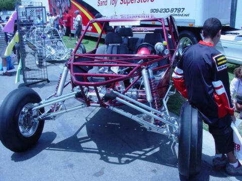 1992 Ford Bronco - A custom dune buggy with a red frame and exposed suspension sits on pavement.
